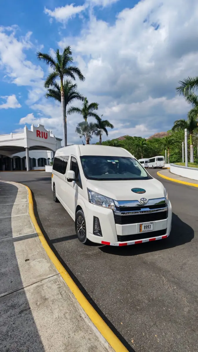 A Tropical Experts Toyota Hiace at the RIU Guanacaste entrance, among palm trees