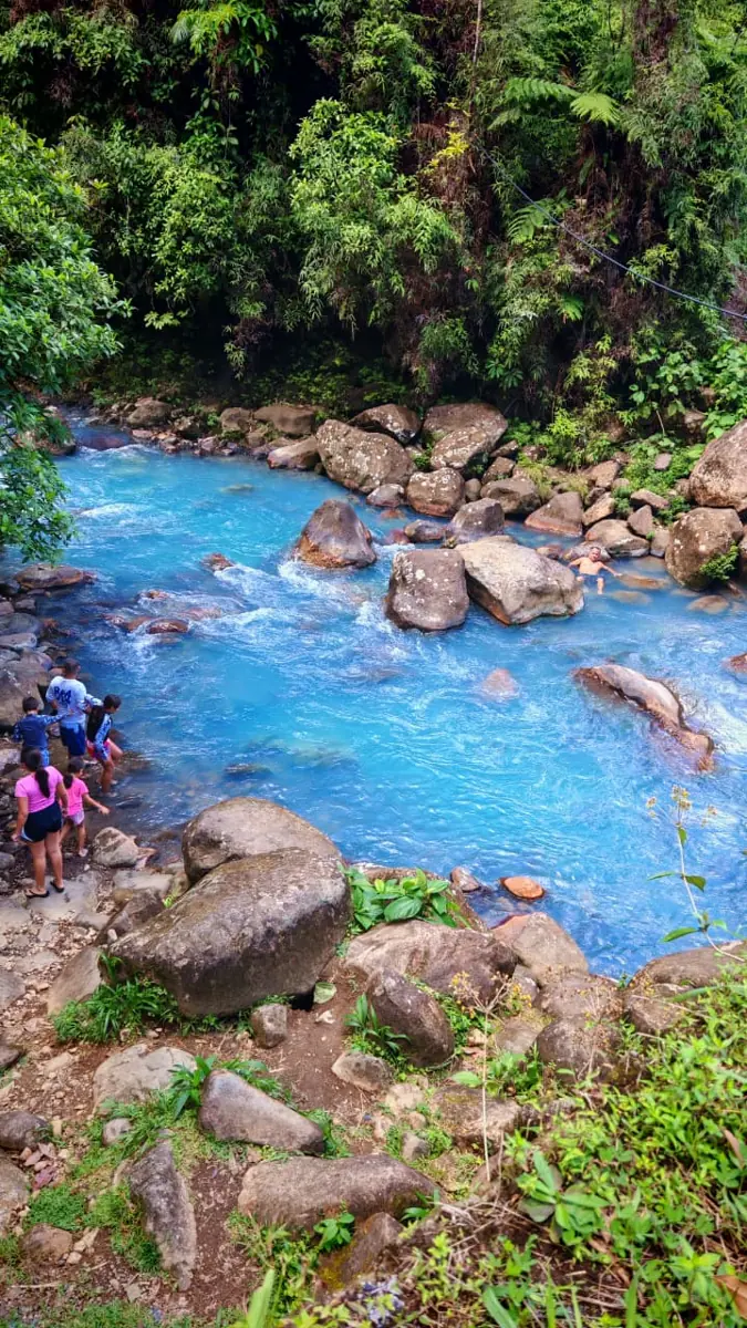The sky-blue water of Río Celeste flowing between boulders