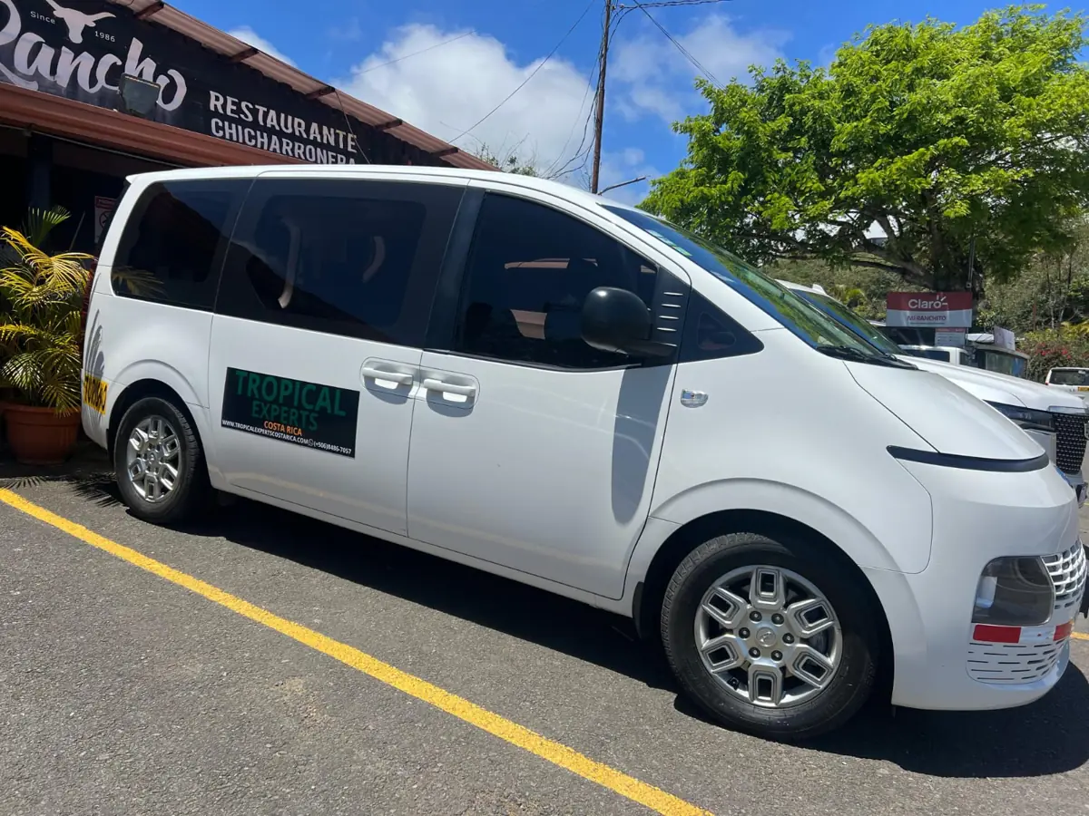 A white Tropical Experts Hyundai Staria parked outside a roadside restaurant