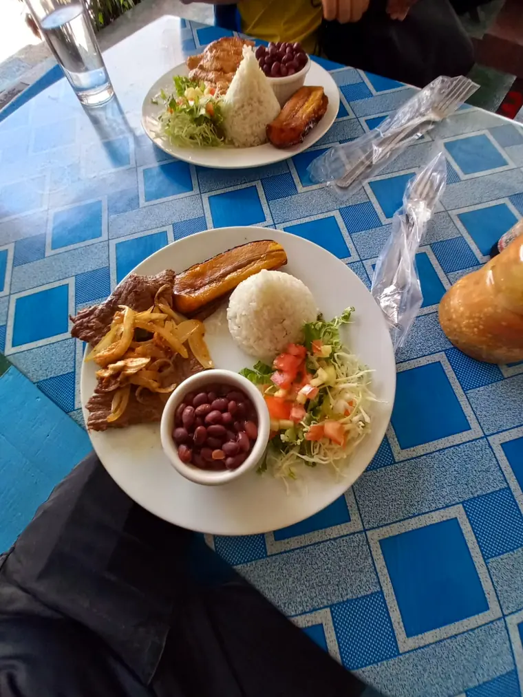 Casado de bistec con frijoles rojos en una soda de mantel azul