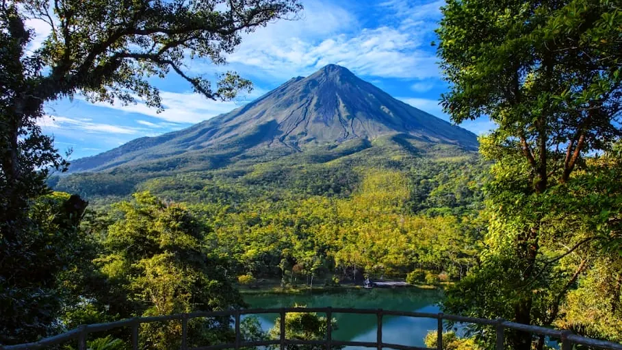 El volcán Arenal desde un mirador de La Fortuna, con la laguna y el bosque en temporada verde