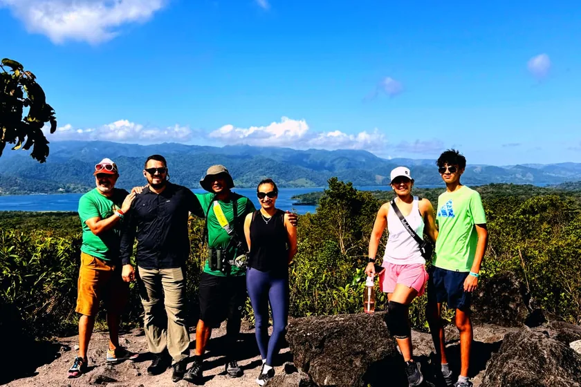 A group of passengers at a lookout with a view of the lake and the mountains
