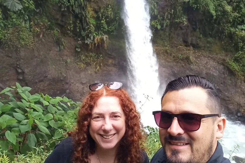 Pasajera y su chofer frente a una catarata, en una parada del recorrido