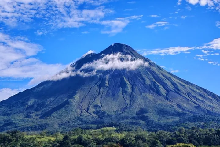 El volcán Arenal sobre potreros verdes camino a La Fortuna